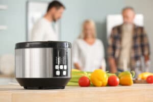 Modern multi cooker with fresh vegetables on table in kitchen