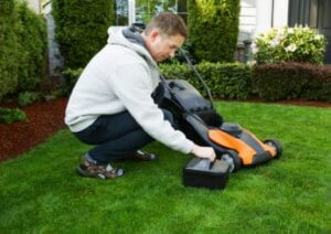 man-putting-a-battery-in-his-lawn-mower