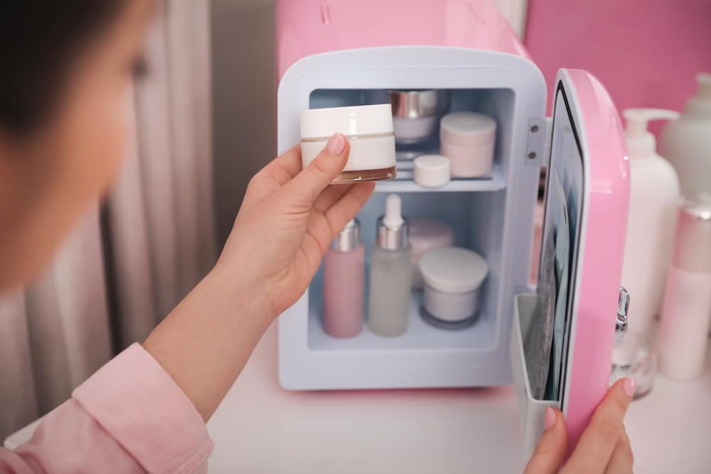 Woman taking cream out of small refrigerator