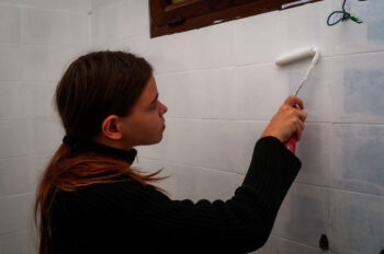 Young woman painting ceramic wall tiles