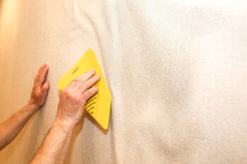 a man using a scraper to install wallpaper