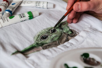painting baby Yoda on a t-shirt